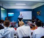 A business seminar with people attentively listening to a speaker in a modern classroom setting.