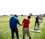 Instructor teaching golf at an outdoor course with students practicing their swings.