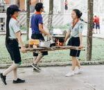 Youth scouts engaging in an outdoor cooking activity, carrying food and pots.