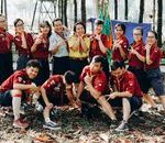 A group of young scouts posing playfully outdoors with their uniforms and badges.